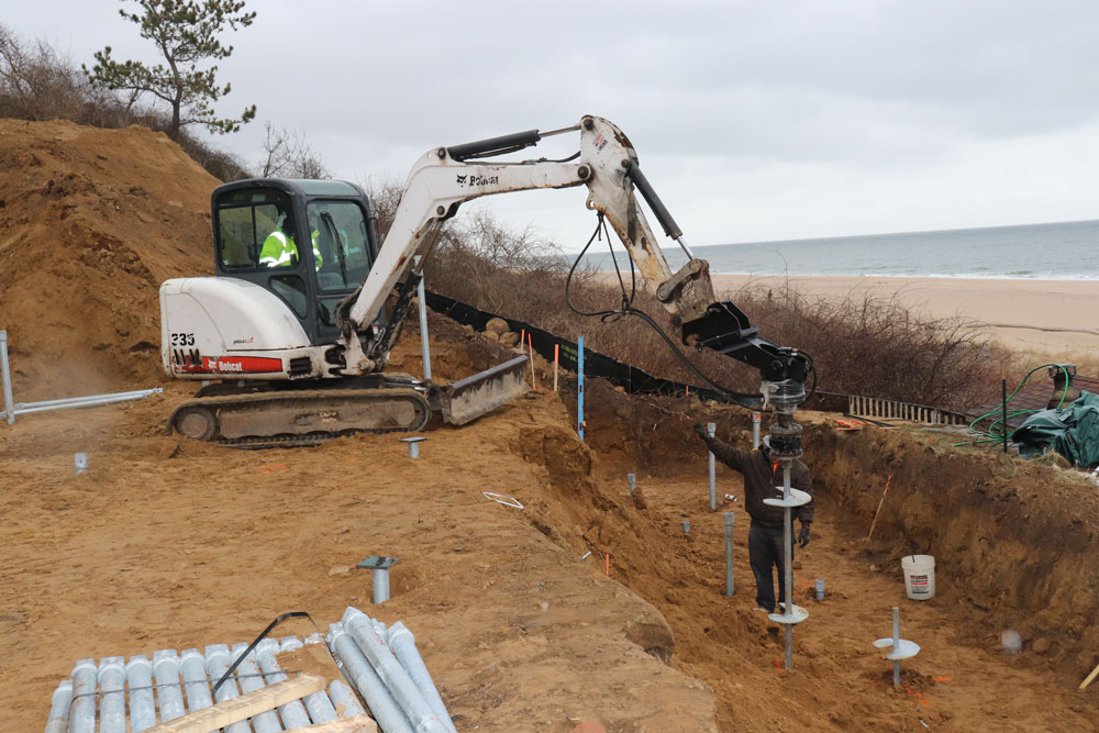 helical piles being driven into ground for retaining walls to protect from flooding and storm surge